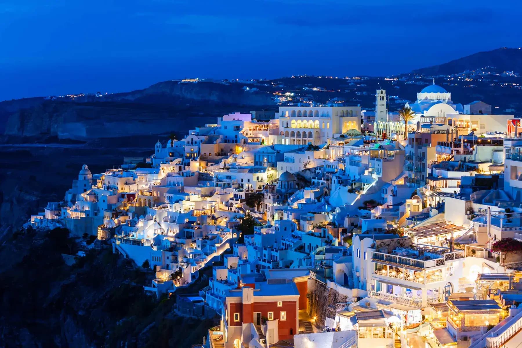 Cliffside Santorini village glowing at blue hour before a Greek cruise