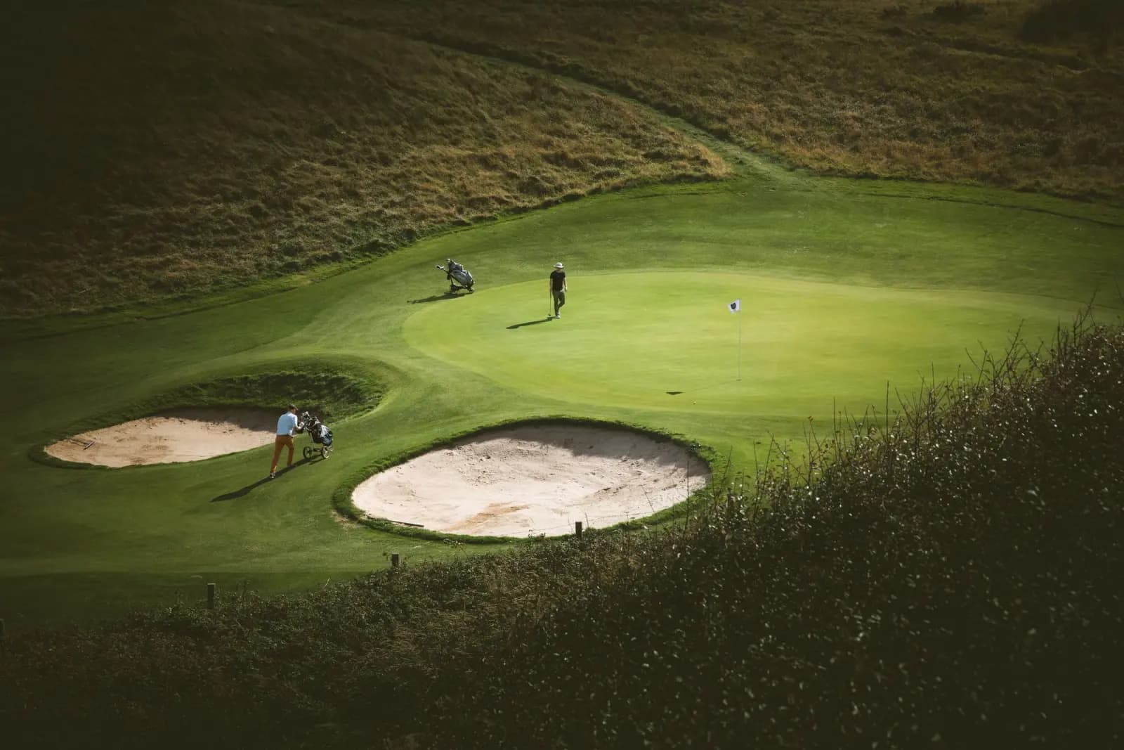 Golfers on a manicured green beside deep bunkers on a Portugal golf tour