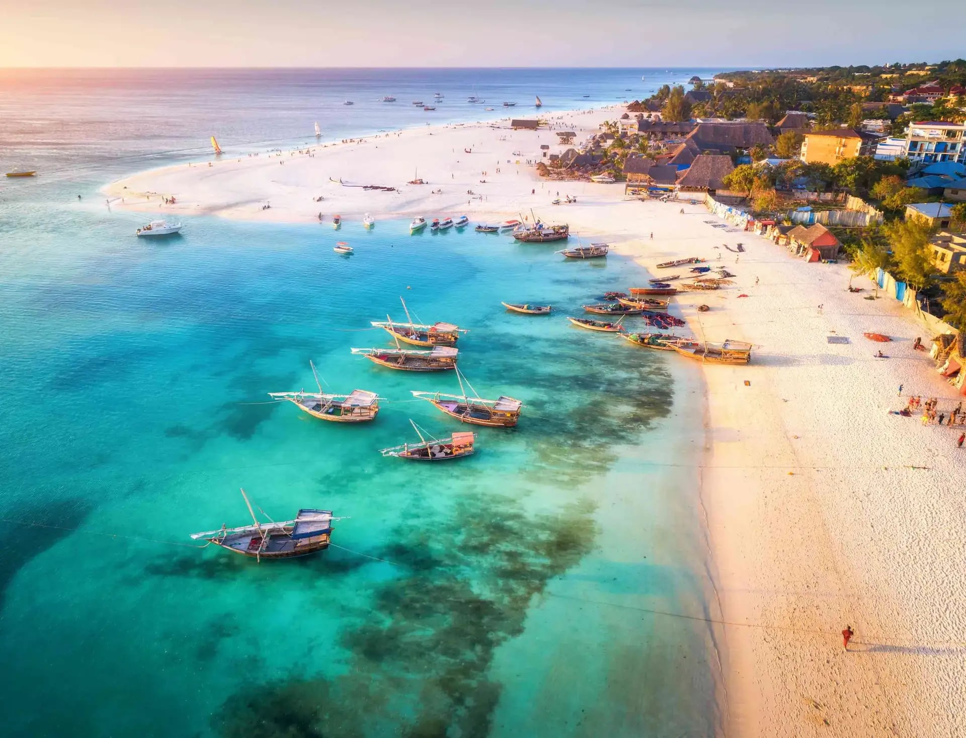 Traditional dhow boats on the turquoise shallows of a white Zanzibar beach