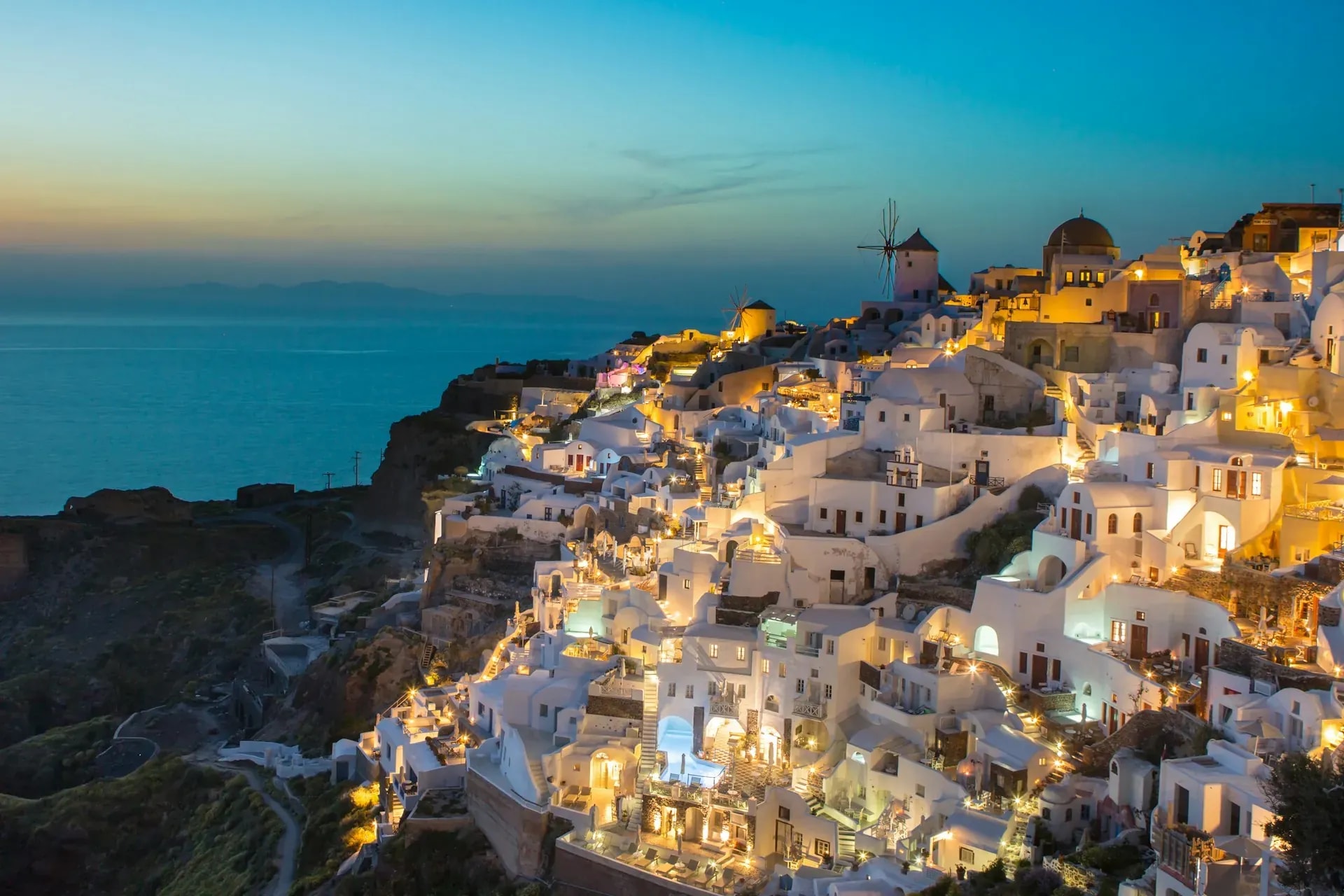 Whitewashed Oia village above the Santorini caldera at sunset, Greece