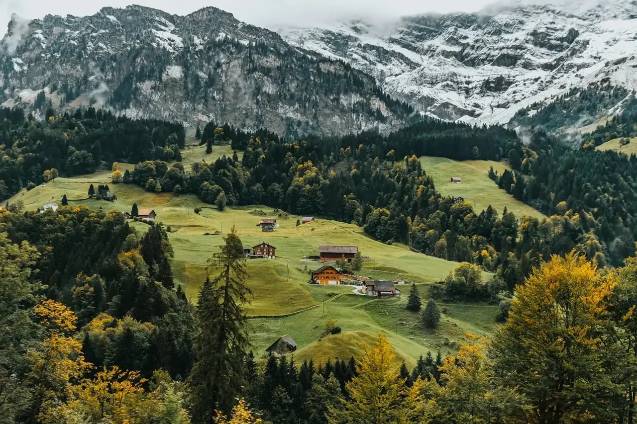 Alpine meadow and chalets beneath snow-capped Swiss peaks