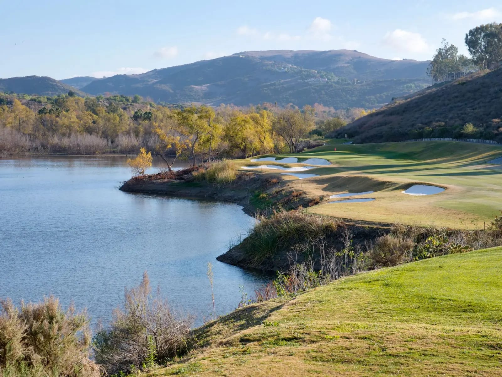 Golf fairway and bunkers beside a lake with mountains behind on the Costa del Sol, Spain