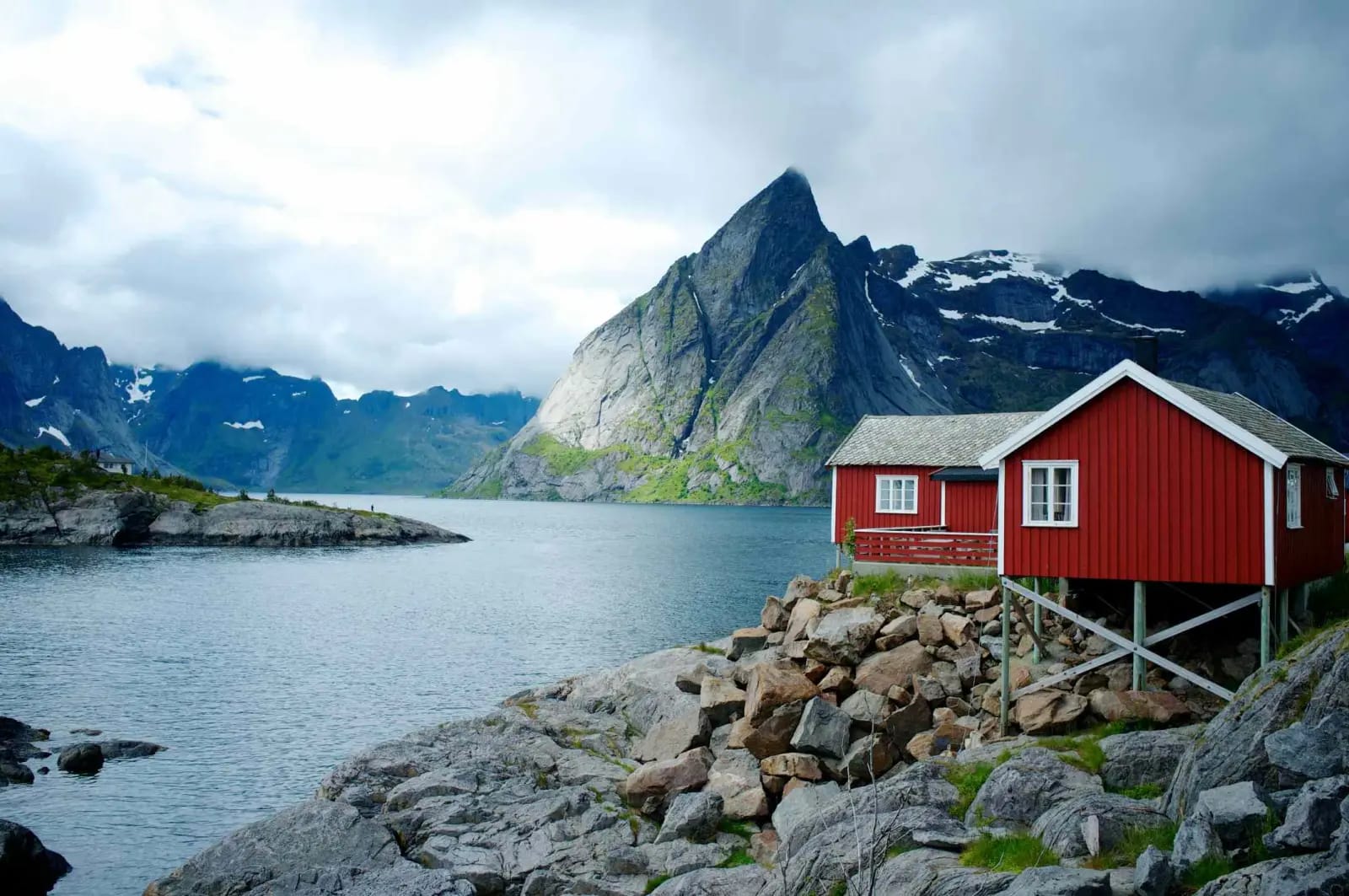 Red rorbu cabins beneath granite peaks at Reine in the Lofoten Islands, Norway